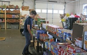 Kendra Peek/kendra.peek@amnews.com Volunteer Nancy Robertson adjusts food on a shelf at the New Hope Food Pantry.