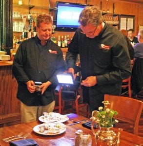 Kendra Peek/kendra.peek@amnews.com Michael Lattin, left, and Dan Davidsaver, right, film and photograph food at Cue on Main Tuesday night. Lattin is the creator and producer of Secrets of Bluegrass Chefs, on which Cue on Main and Nellie Burton's will be featured in an April airing of the show.